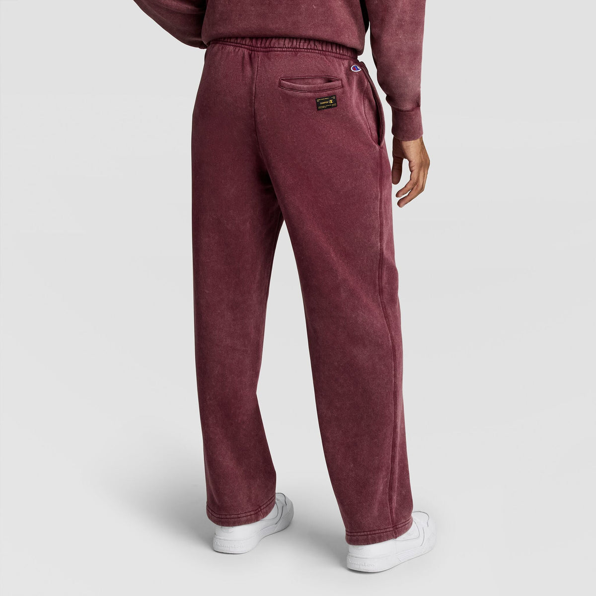 A person viewed from behind wearing maroon Mineral Wash Open Hem Pant sweatpants with an open hem and a back pocket.