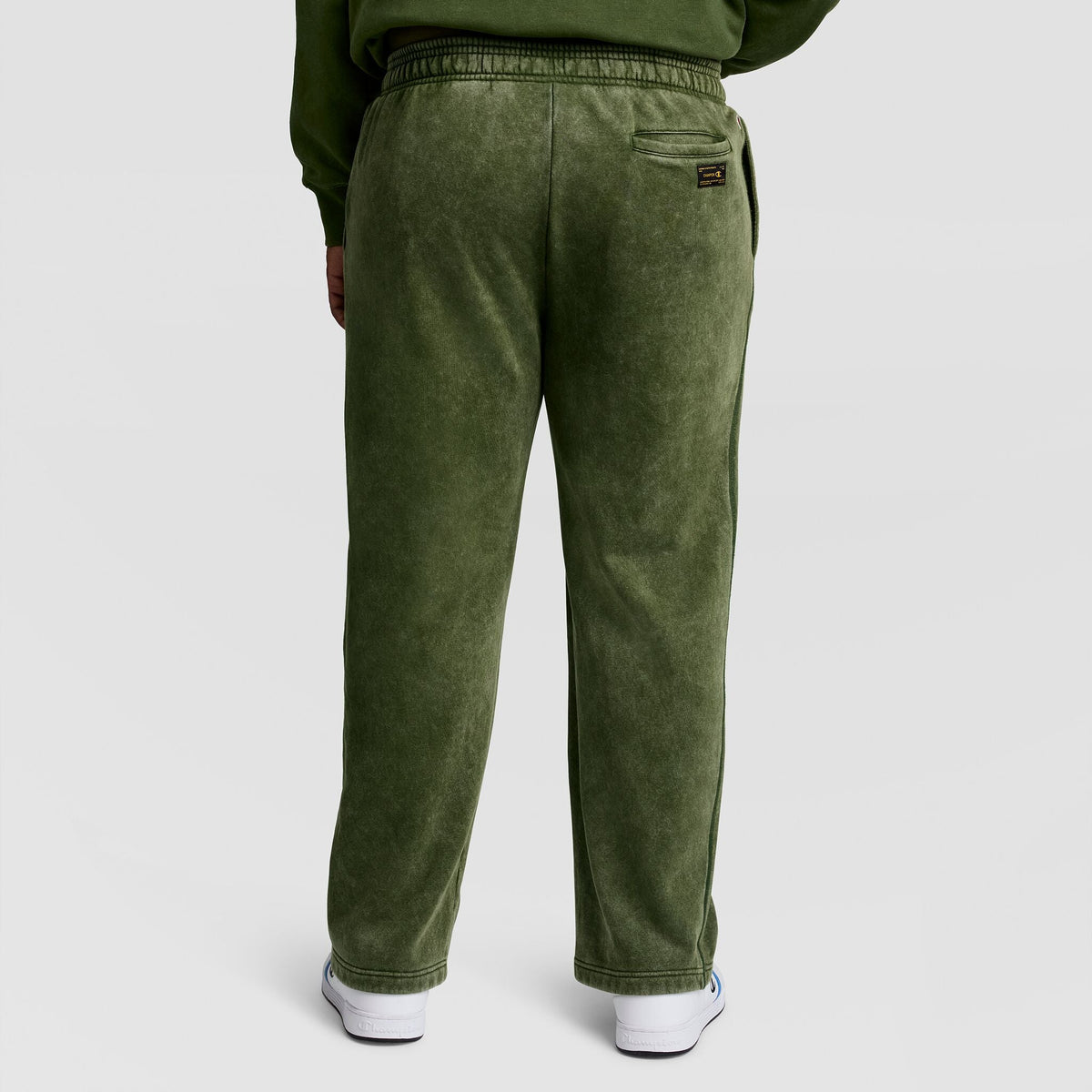 Back view of olive green Champion Mineral Wash Open Hem Pant featuring an open hem and a back pocket with a small logo patch.