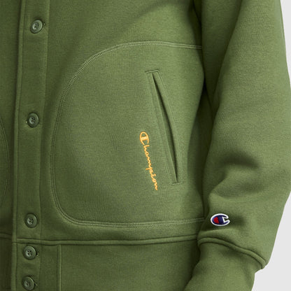 Close-up of a green vintage-inspired Champion Fleece Baseball Jacket featuring a front pocket with a yellow Champion logo, plus a small Champion C patch on the sleeve. The jacket is designed with visible buttons and detailed stitching, echoing the classic varsity jacket style.