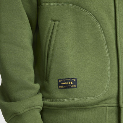 Close-up of a green Champion Fleece Baseball Jacket inspired by vintage athletic style, highlighting a side pocket, ribbed cuff, and a small rectangular Champion brand label near the pocket.