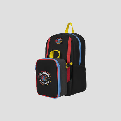Kids’ Mode Lunch Kit & Backpack Combo by Champion—a black athletic backpack for kids with red, yellow, and blue accents, featuring a Champions patch and a detachable insulated lunch box on the front. Both pieces are designed with colorful zippers and displayed against a plain gray background.