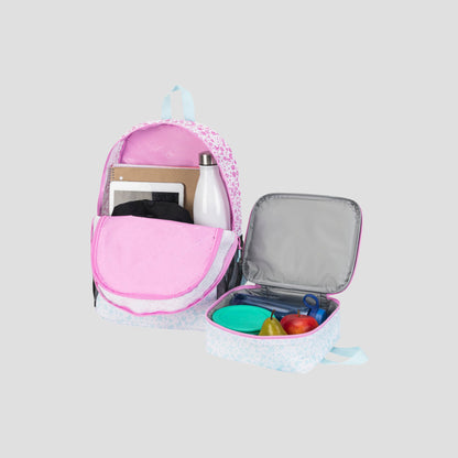A Champion Kids’ Mode Lunch Kit & Backpack Combo in pink and white—shown with a water bottle, tablet, and notebook inside the backpack—sits beside an open insulated lunch kit holding a green container, apple, pear, and blue fork, all arranged on a light gray background.