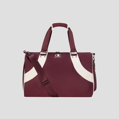 The Champion Oracle Duffel Bag in maroon, featuring white curved stripes, top handles, a shoulder strap, and a small Champion logo on the front, is displayed against a plain light gray background. This versatile gym bag is ideal for both workout sessions and travel.