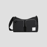 The Champion Quartz Small Messenger Bag, crafted from lightweight black nylon, features two front zippered pockets, a white rectangular patch, and an adjustable strap. It is photographed against a plain light gray background.