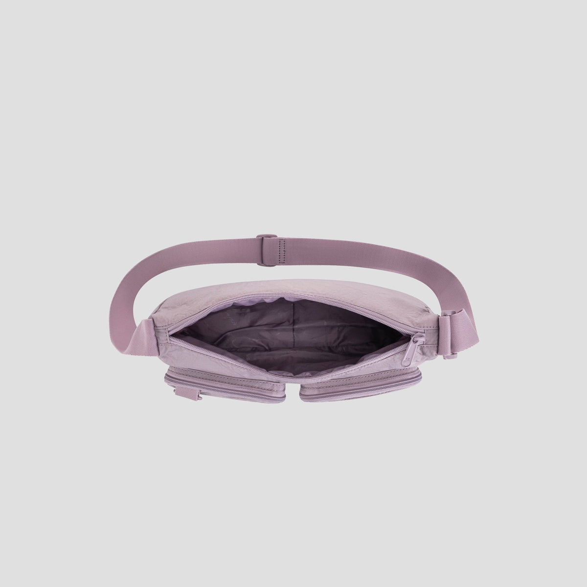 A top view of the open Champion Quartz Small Messenger Bag in light purple, made from lightweight nylon with a wide strap, showcasing its empty, spacious interior and zippered compartments against a plain gray background—ideal as a stylish crossbody messenger bag for travel or everyday use.