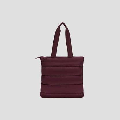 The Champion Quilted Billie Tote is a stylish, dark maroon tote bag featuring padded handles, vertical quilted stitching, and a secure zipper closure—perfect for everyday use. It is displayed against a plain light gray background.