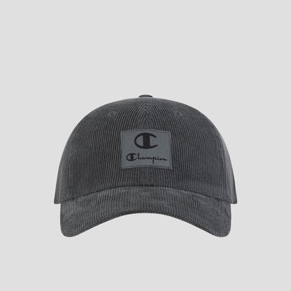 Introducing the Ridge Corduroy Adjustable Cap by Champion—a dark grey vintage-inspired baseball cap crafted from corduroy. Featuring a relaxed fit, curved brim, and an adjustable back closure for custom comfort, this cap showcases a rectangular front patch with the iconic Champion logo and text. Photographed on a plain white background.