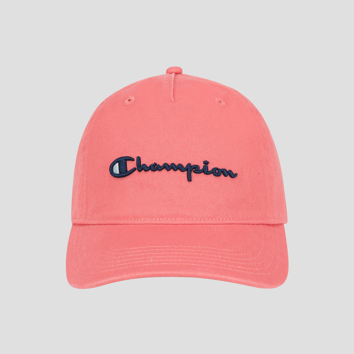 The Champion Script Embroidery Adjustable Cap in pink, made from washed cotton twill, features “Champion” embroidered in navy blue on the front and is displayed against a light gray background.