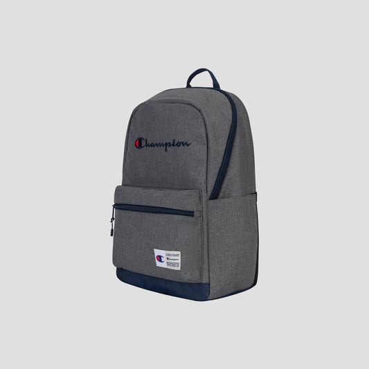 The Champion System Backpack in gray features a front zip pocket, navy blue bottom, and navy blue zipper pulls. Designed for versatility, it offers multiple storage compartments and a padded laptop sleeve for secure organization. The embroidered Champion logo appears on the upper front, while a small white label accents the lower front.