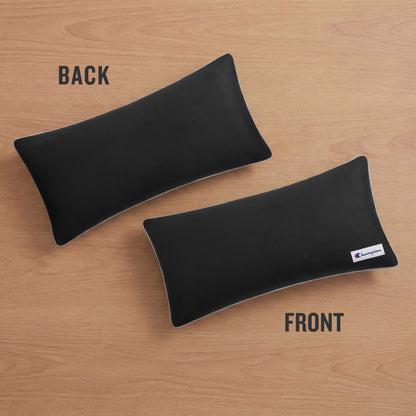 Two rectangular black Faux Wool Body Pillows by Champion with plush polyester fill rest on a wooden surface; one labeled BACK is unbranded, while the other labeled FRONT displays a small Champion logo tag on the bottom right corner.