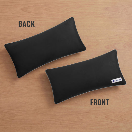 Two rectangular black Faux Wool Body Pillows by Champion with plush polyester fill rest on a wooden surface; one labeled BACK is unbranded, while the other labeled FRONT displays a small Champion logo tag on the bottom right corner.