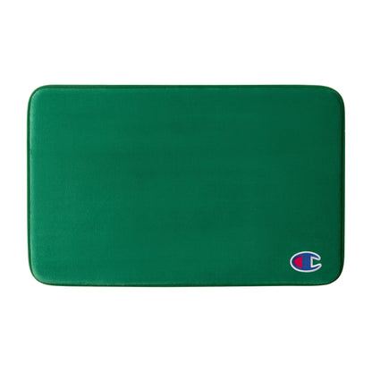 A green rectangular Logo Patch Memory Foam Bath Mat by Champion, featuring rounded corners and a small Champion logo patch on the bottom right, designed with plush memory foam for enhanced comfort and a skid-resistant backing to keep it securely in place.