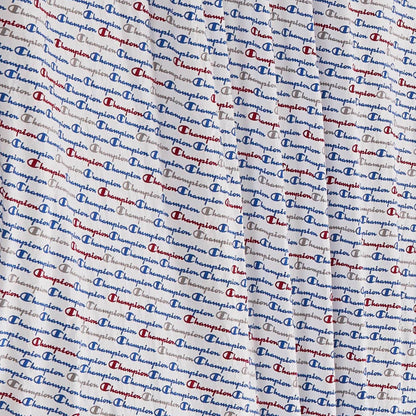 Close-up of the super-soft Printed Microfiber Sheet Set by Champion, featuring a repeating blue and red Champion logo pattern on a white background. Light wrinkles and folds in the fabric enhance the cozy appeal of these branded sheets.