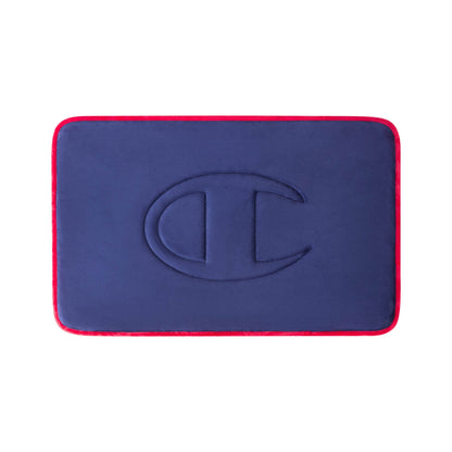 A rectangular navy blue Quilted Logo Memory Foam Bath Mat by Champion, featuring rounded corners, red edges, and an embossed large C logo in the center, displayed against a white background.