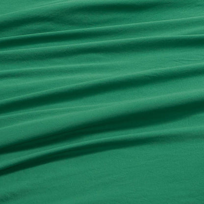 Champion’s Elastic Logo Microfiber Sheet Set in green features a smooth, soft texture with several horizontal folds and wrinkles that create a distinctive, draped appearance. The microfiber material displays gentle shading and a plush feel, enhancing the set’s textured look.
