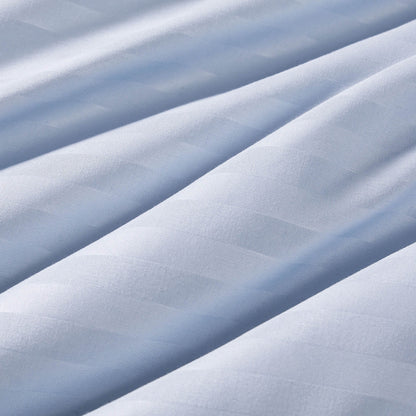 Close-up of smooth, light blue fabric with gentle diagonal folds and a subtle, horizontal striped texture. The material appears soft and slightly shiny, reminiscent of the fabric used in the Champion Blue Cooling Down Alternative Comforter.