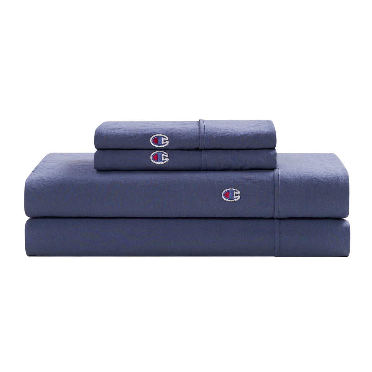 A neatly folded Champion Embroidery Patch Microfiber Sheet Set in dark blue, including bed sheets and pillowcases crafted from soft microfiber fabric, each adorned with a small embroidered Champion logo, stacked on a white background.