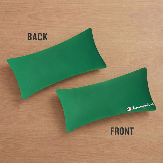 Two green rectangular Champion Jersey Body Pillows rest on a wooden surface—one displays the plain green back, while the other reveals the iconic white and red Champion logo on the front. These sporty body pillows add an athletic accent to any space, reminiscent of the comfort found in your favorite jersey knit.
