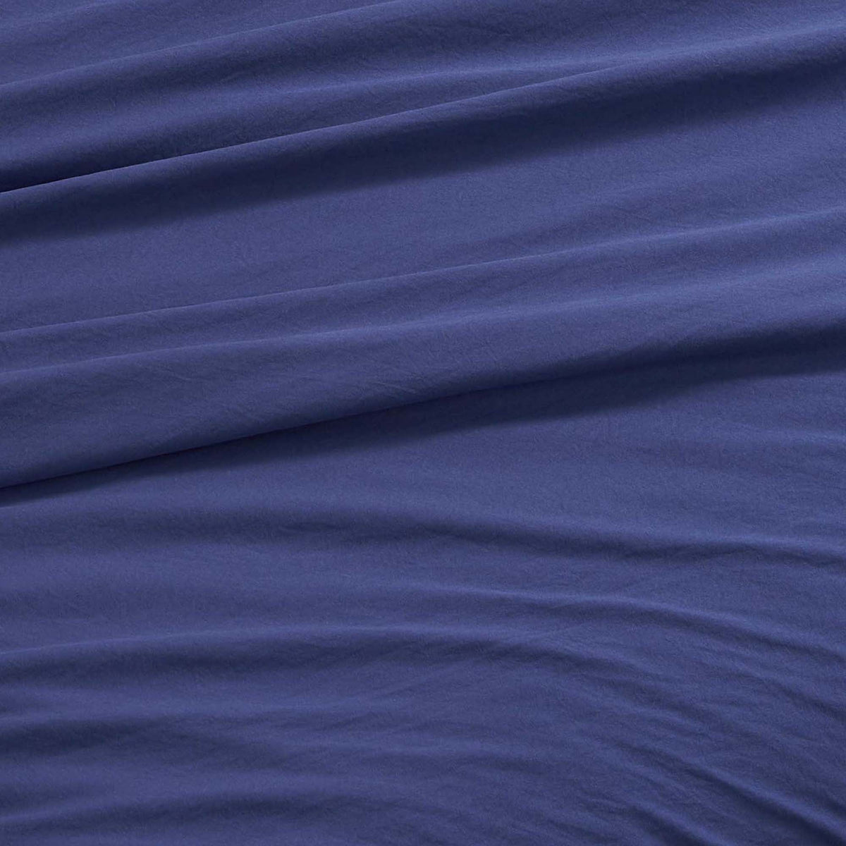 A close-up of the Champion Elastic Logo Microfiber Sheet Set in blue, featuring gentle diagonal folds and a soft texture that exudes smoothness and comfort—beautifully conveying the inviting appeal of this microfiber bedding.