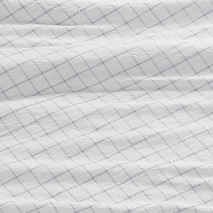 A close-up of a white fabric with a blue grid pattern, slightly wrinkled and textured, shows intersecting thin blue lines—these Champion Printed Microfiber Sheet Sets deliver both everyday comfort and stylish printed design.