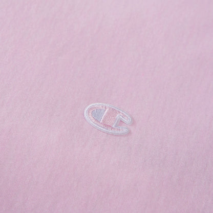 Close-up of a light pink fabric with a small, white embroidered C logo near the center, representing the Champion brand—an ideal accent for those looking to add a stylish touch to their Champion Reversible Solid Jersey Comforter Set.