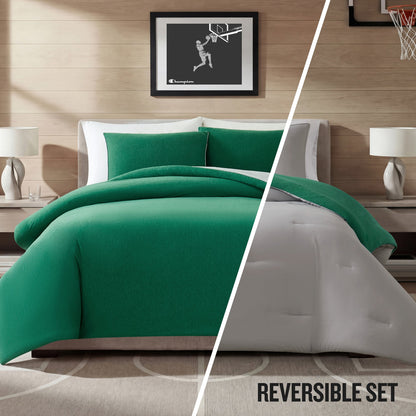 A modern bedroom featuring a bed dressed in the Champion Reversible Solid Jersey Comforter Set in green and white. The space includes two nightstands, matching lamps, and framed basketball artwork. Text reads: REVERSIBLE SET.