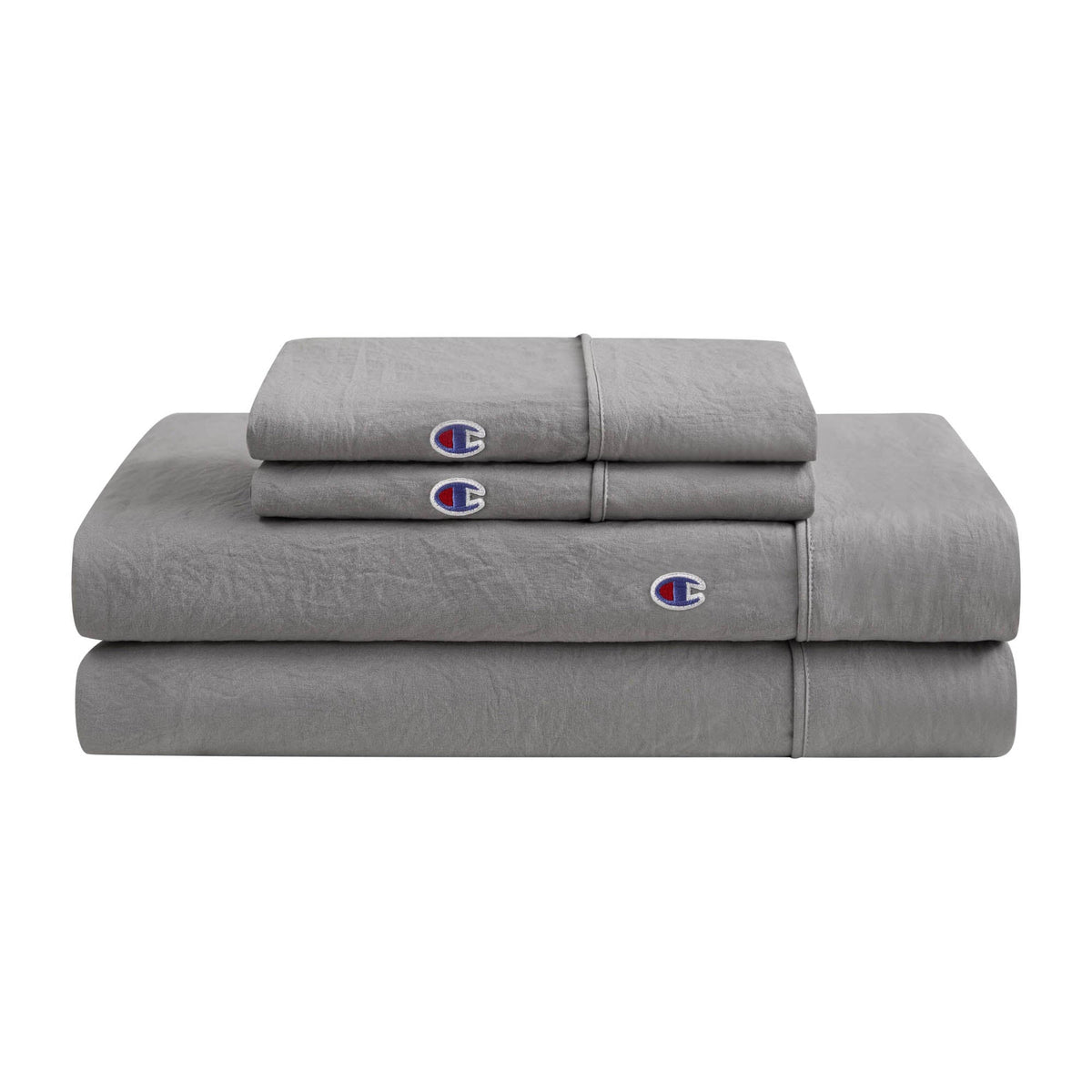 A neatly folded stack of Champion Embroidery Patch Microfiber Sheet Set in gray, featuring bedding sheets and pillowcases adorned with the signature blue, red, and white embroidered C logo. This set offers comfort and iconic Champion style for your bed.